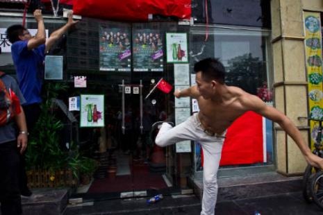 صيني يركل باب محل ياباني في مدينة شينزن جنوب الصين أمس (كيتا فان ــ رويترز)