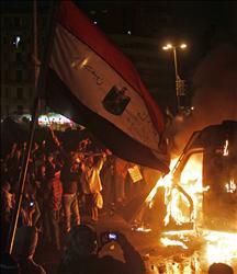 متظاهرون أمام آلية للشرطة أضرمت فيها النيران في القاهرة أمس (أ ب أ) 
