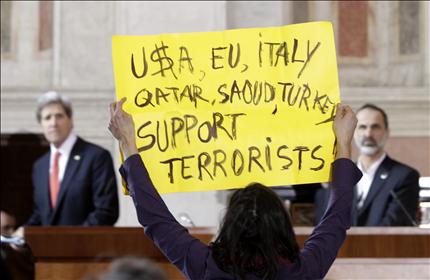ناشطة سلام تحمل لافتة كتب عليها «الولايات المتحدة، الاتحاد الأوروبي، ايطاليا، قطر، السعودية، تركيا، يدعمون الإرهابيين» خلال المؤتمر الصحافي لكيري والخطيب في روما امس (ا ب) 