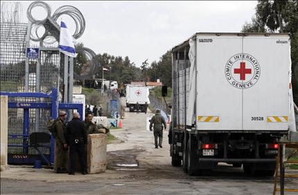 شاحنات تابعة للصليب الاحمر الدولي خلال نقلها تفاح الجولان عبر معبر القنيطرة الى سوريا امس (رويترز) 