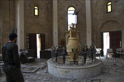 مسلح داخل كنيسة ارمنية تضررت جراء الاشتباكات في دير الزور امس الاول (رويترز) 