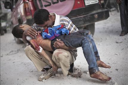 سوري يحتضن جثة طفله قرب مستشفى دار الشفاء بعد التفجيرات الانتحارية في حلب أمس (أ ب) 