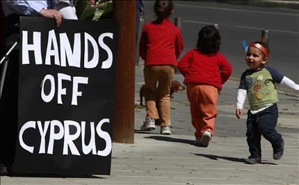 اطفال يمرون امام لافتة كتب عليها «ارفعوا ايديكم عن قبرص» في نيقوسيا أمس (أب) 