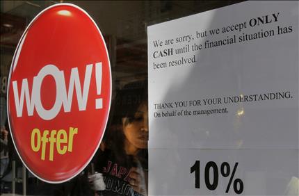 ورقة ملصقة على أحد المتاجر القبرصية يطلب «الدفع نقداً حتى انتهاء الأزمة. شكراً لتفهمكم» في نيقوسيا أمس(رويترز) 