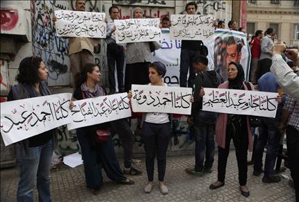 مصريون يحملون لافتات تحمل أسماء الناشطين المطلوب القبض عليهم أمام دار القضاء في القاهرة، أمس (رويترز) 