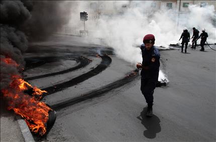 عناصر شرطة يخلون الطريق من الإطارات المشتعلة في جدحفص في البحرين أمس (أ ب) 