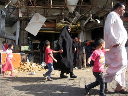 عائلة عراقية تمر أمام مخبز تعرض لأضرار نتيجة تفجير استهدف مدينة الصدر في بغداد أمس (أ ب أ) 