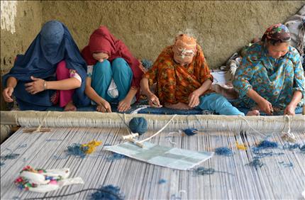 أفغانيات يعملن في صناعة السجاد في مخيم خراسان للاجئين قرب إقليم بيشاور في شمال باكستان أمس (أ ف ب) 
