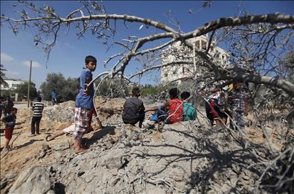 أطفال فلسطينيون في موقع استهدفته إحدى الغارات الإسرائيلية في الزوايدة في وسط قطاع غزة أمس (أ ب) 