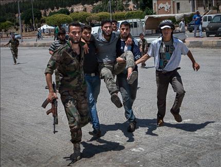 مسلحون يحملون زميلاً لهم باتجاه معبر باب الهوى مع تركيا بعد إصابته برصاص لاجئين سوريين غاضبين من المسلحين أمس الاول (ا ف ب) 