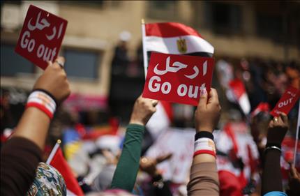 متظاهرون ضد الرئيس المصري يحملون بطاقات حمراء كتب عليها «إرحل» في ميدان التحرير أمس (رويترز) 