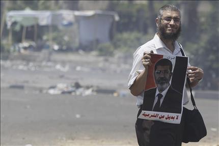 عضو في «الاخوان» يحمل صورة لمرسي في القاهرة امس (رويترز) 