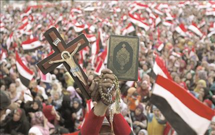مصرية تحمل نسخة من القرآن وصليباً خلال تظاهرة ضد مرسي في ميدان التحرير في القاهرة امس (رويترز) 