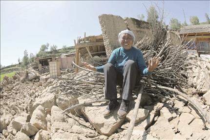 سيدة تبكي وهي جالسة على أنقاض منزلها في دينشي في مقاطعة غانسو أمس (أ ف ب) 