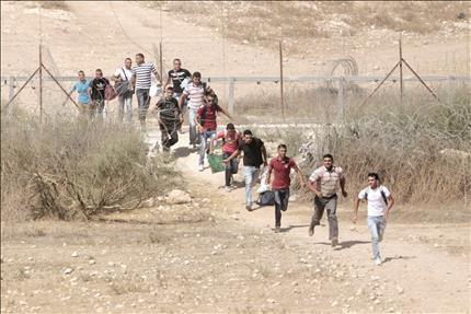 عمال فلسطينيون يقطعون الشريط الفاصل بين الأراضي الفلسطينية في جنوب الضفة الغربية باتجاه مدينة بئر السبع في أراضي الـ48 (رويترز) 