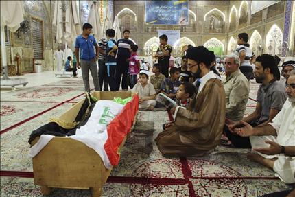 عراقيون يصلون على نعش أحد الضحايا الذين سقطوا في الهجوم على "سجن الحوت" في مرقد الإمام علي في مدينة النجف أمس الأول (رويترز) 