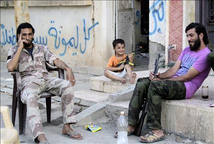طفل يجلس بين مسلحين في دير الزور امس الاول (رويترز) 