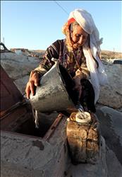 فلسطينية تملأ الدلو بمياه البئر قرب الكهف الذي تعيش فيه في خربة غوين في جنوب الخليل في الضفة الغربية امس الأول (ا ب ا) 