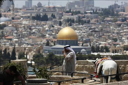 فلسطيني يقف في منطقة مطلة في جبل الزيتون في القدس المحتلة، ويظهر مسجد قبة الصخرة (رويترز) 
