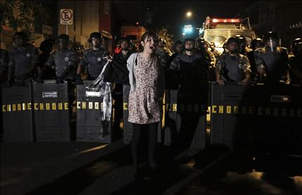 برازيلية تنتمي إلى مجموعة "بلاك بوكس" تهتف بشعارات من أمام قوات الشرطة خلال التظاهرة في مدينة ساو باولو أمس (رويترز) 