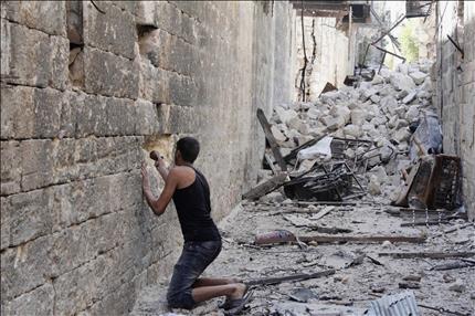 مسلح يضع عبوة في جدار لفتح ثغرة فيه من عمليات اجل القنص في المدينة القديمة في حلب امس (رويترز) 