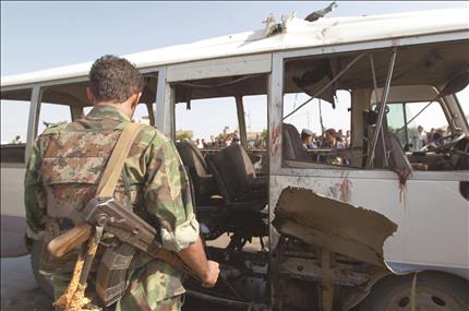 جندي يمني يتفقد حافلة القوات الجوية المدمرة في صنعاء أمس (أ ف ب) 