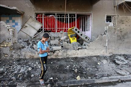 فتى عراقي يتفقد أمس، أثار أحد التفجيرات التي استهدفت العاصمة بغداد أمس الأول (رويترز) 