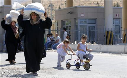 طفلتان تلهوان على دراجة هوائية خلال فرار عائلة سورية الى تركيا امس (رويترز) 