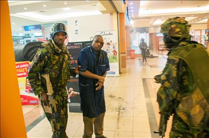 أحد المصابين إلى جانب عناصر من القوات الكينية بعد الهجوم على المركز التجاري في نيروبي أمس الأول (أ ف ب) 