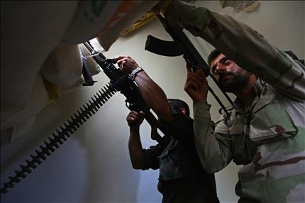 مسلحان سوريان يصوبان سلاحيهما في منطقة بستان القصر في حلب أمس (رويترز) 