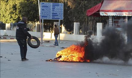 متظاهر يحرق الإطارات خلال اشتباكات بين الشرطة ومتظاهرين في سليانة في تونس أمس (رويترز) 