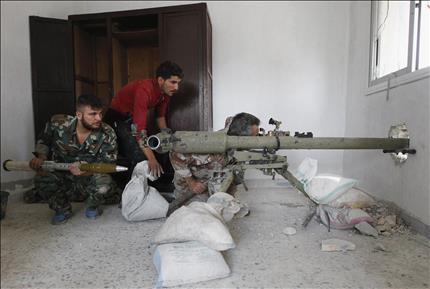 مسلحون يستعدون لاطلاق قذيفة من داخل احد المنازل في حي الاشرفية في حلب امس (رويترز) 