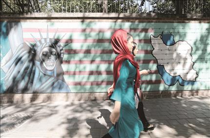 إيرانية تمر أمام حائط رسم عليه تمثال الحرية الأميركي بشكل ساخر أمام السفارة الأميركية في طهران أمس (أ ف ب) 