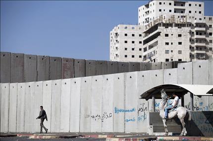 فلسطيني يمتطي حصاناً بالقرب من جدار الفصل العنصري الذي يفصل مخيم شعفاط عن القدس المحتلة أمس (ا ب ا) 