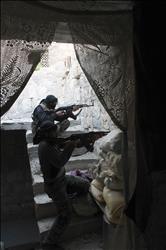 مسلحان خلال اشتباكات مع القوات السورية في حي كرم الجبل في حلب امس (رويترز) 