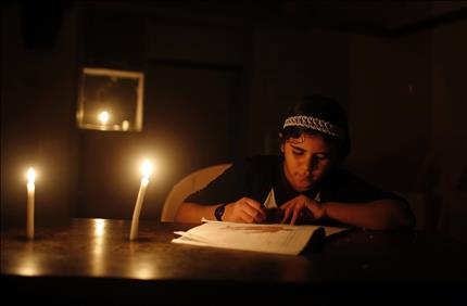 طفلة فلسطينية تدرس على ضوء الشمع في شمال قطاع غزة أمس (رويترز) 