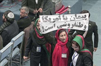 أفغانية من الـ"لويا جيرغا" ترفع لافتة كتب عليها "الاتفاق مع أميركا هو بيع للوطن" خلال إلقاء قرضاي لكلمته في كابول أمس (أ ب) 