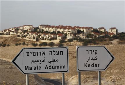 مستوطنة «معالي أدوميم» تظهر خلف لافتتين استيطانيتين قرب القدس المحتلة أمس. (رويترز) 
