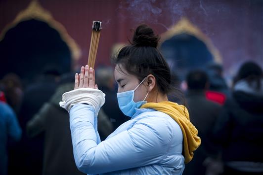 صينية تشعل البخور وتصلي لطلب الحظ في السنة الجديدة في العاصمة بكين أمس (ا ب ا)