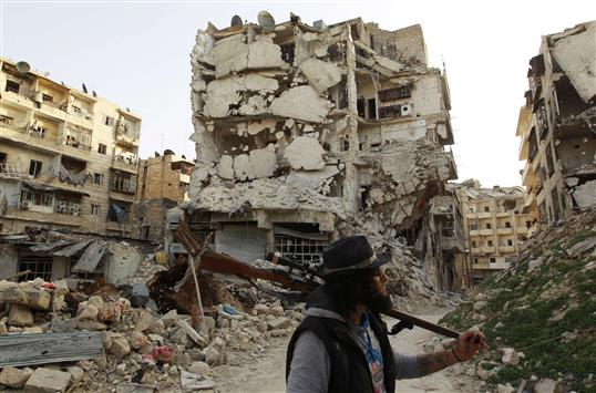 رسام وشم سابق يحمل سلاحا بين مبان مدمرة في حي كرم الجبل في حلب الاحد الماضي (رويترز)