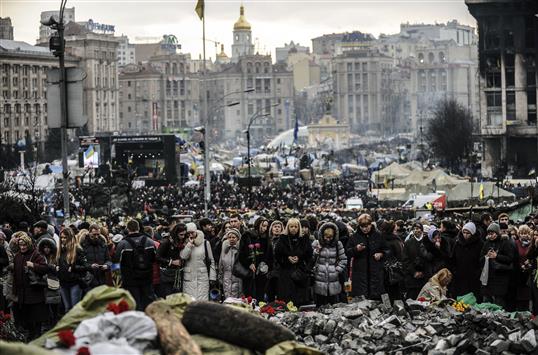 أوكرانيون يزورون ساحة الاستقلال في كييف أمس، حيث قتل متظاهرون خلال الاحتجاجات (أ ف ب)