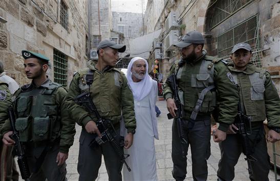 فلسطيني يقف خلف عناصر من شرطة الاحتلال أثناء قطعهم لأحد الأزقة المؤدية إلى المسجد الأقصى في القدس المحتلة أمس الأول (رويترز)