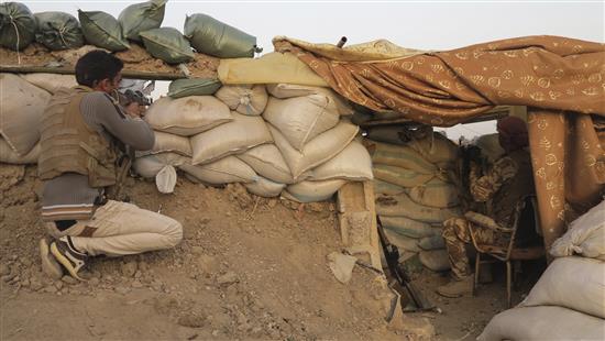 مسلح من العشائر وعنصر من قوات الأمن العراقية يشاركان في اشتباكات في محافظة الانبار أمس (رويترز)