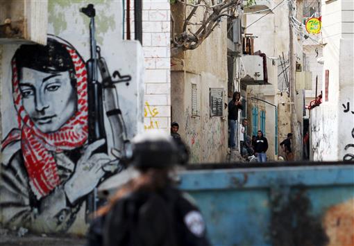 جندي اسرائيلي يصوب نحو فتية فلسطينيين بالقرب من مخيم عايدة قرب بيت لحم أمس ويبدو رسم للمناضلة ليلى خالد (أ ف ب)