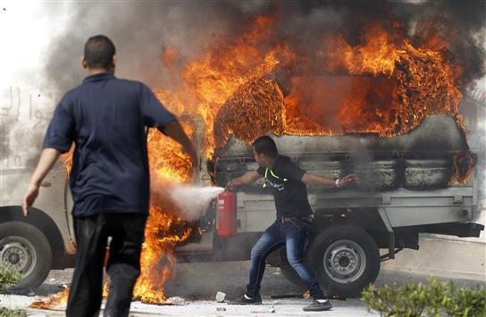 عنصر من الأمن يحاول إخماد حريق أضرمه مؤيدو "الاخوان" بسيارة للشرطة في جامعة الأزهر أمس (رويترز)