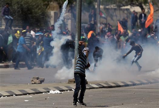 فلسطيني يرمي حجارة باتجاه شرطة الاحتلال خلال الاشتباكات قرب سجن عوفر في الضفة الغربية أمس (أ ف ب)
