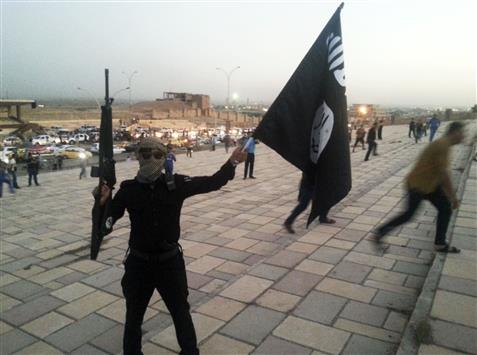 مسلح من «داعش» يحمل علم التنظيم في الموصل في 23 حزيران الماضي (رويترز)