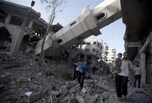 فلسطينيون يسيرون تحت مئذنة جامع دمرته قوات الاحتلال الاسرائيلي في غزة امس (ا ف ب)