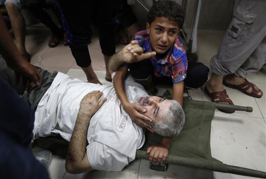 طفل يغمر أباه الذي أصيب جراء القصف في حي الشجاعية أمس (رويترز)