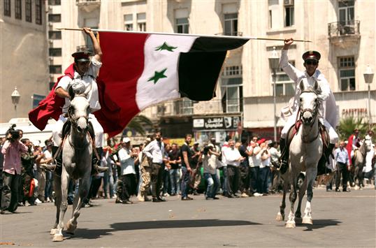 فارسان يحملان العلم السوري في اطار عرض نظمته وزارة الرياضة في دمشق امس (ا ب ا)